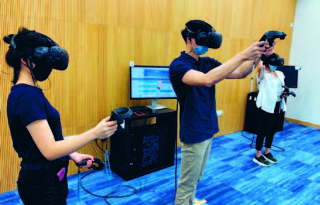 Medical students donning VR goggles and wielding hand-held controllers for the PASS-IT session.