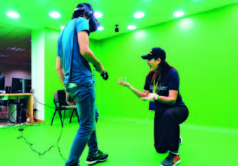 Assoc Prof Stella Tan (right) teaching a student to navigate through a crime scene with VR.