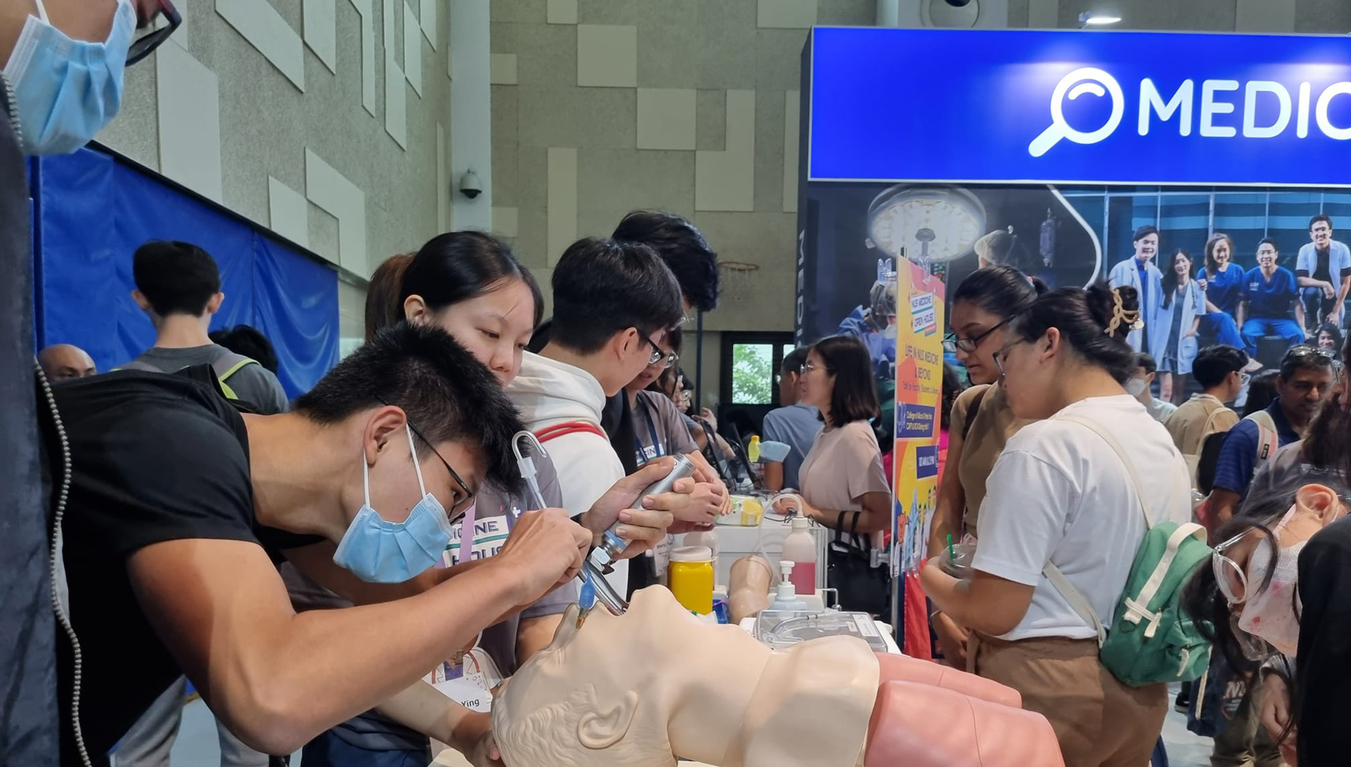 A visitor attempting an intubation procedure using an anatomical model at the NUS Medicine demonstration.
